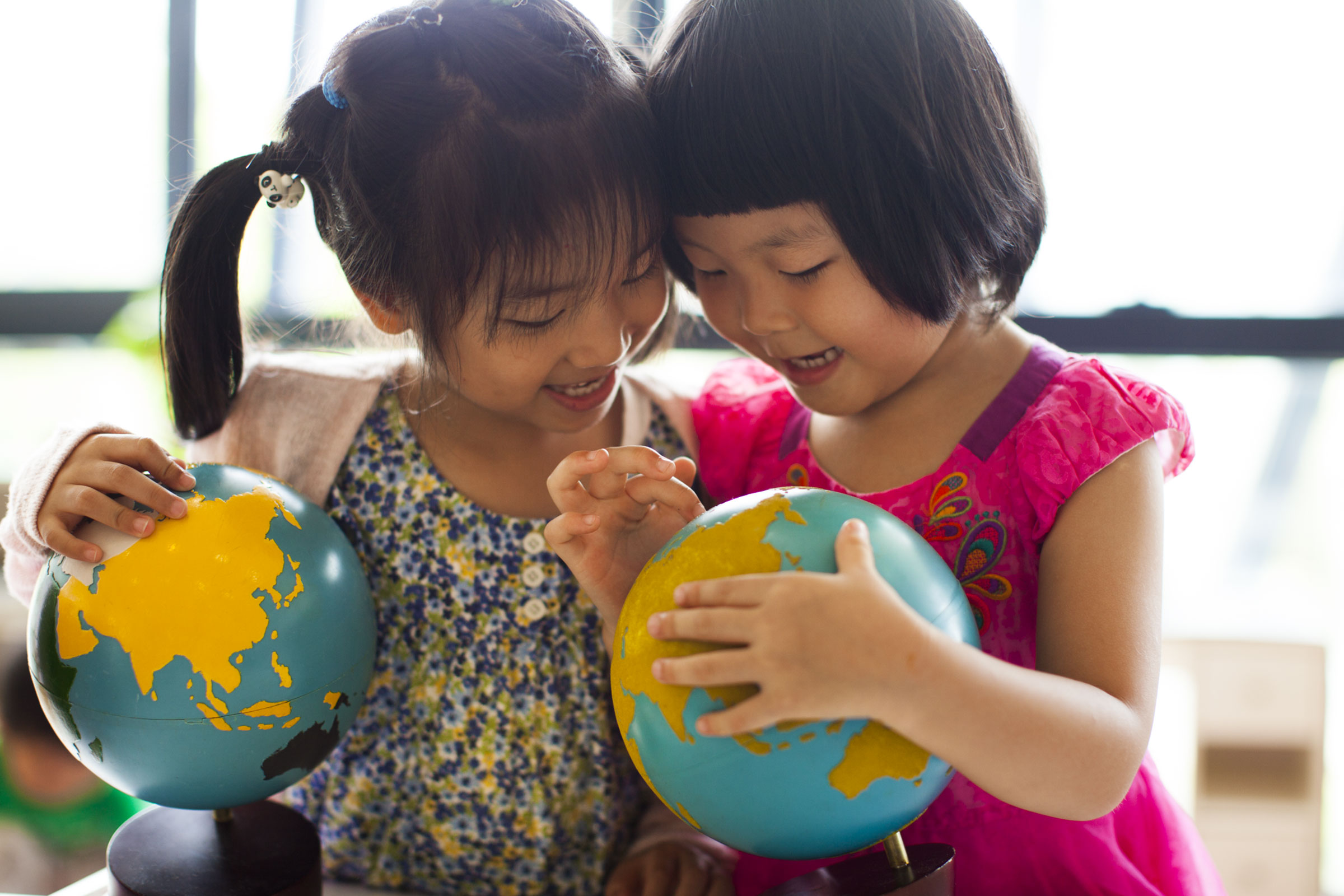 Children in a Montessori classroom holding globes
