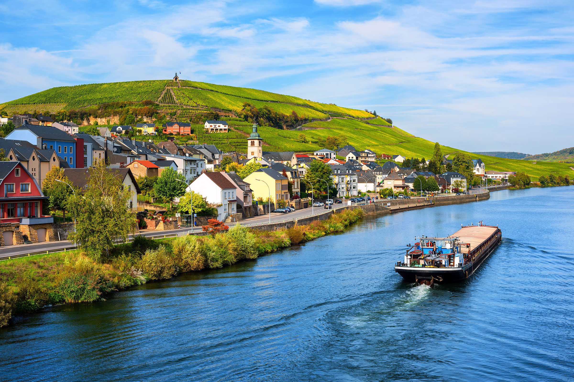 Moselle river by Wormeldange, Luxembourg country, with vineyard hills and a cargo barge ship