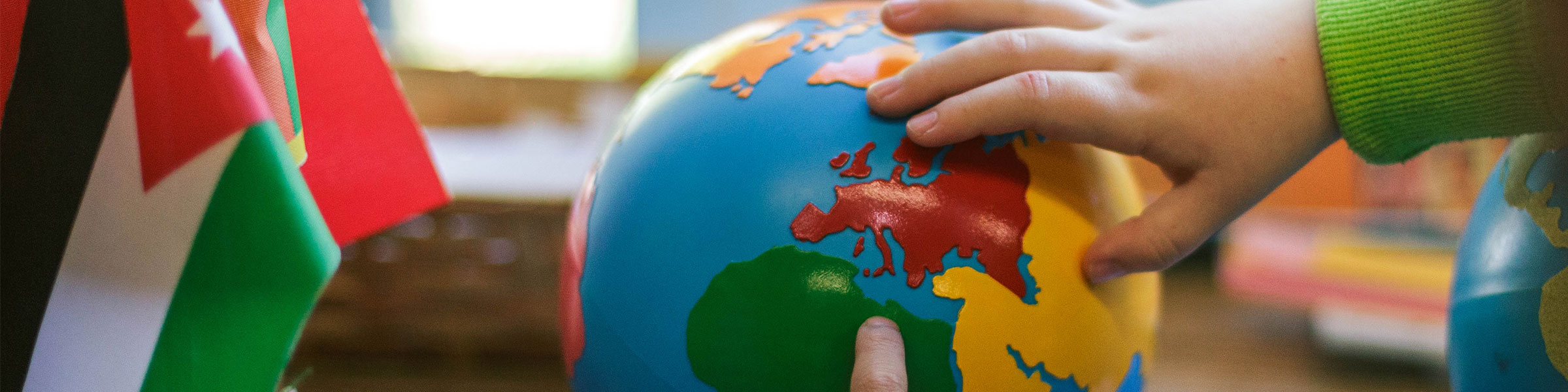 Montessori classroom child's hand on globe