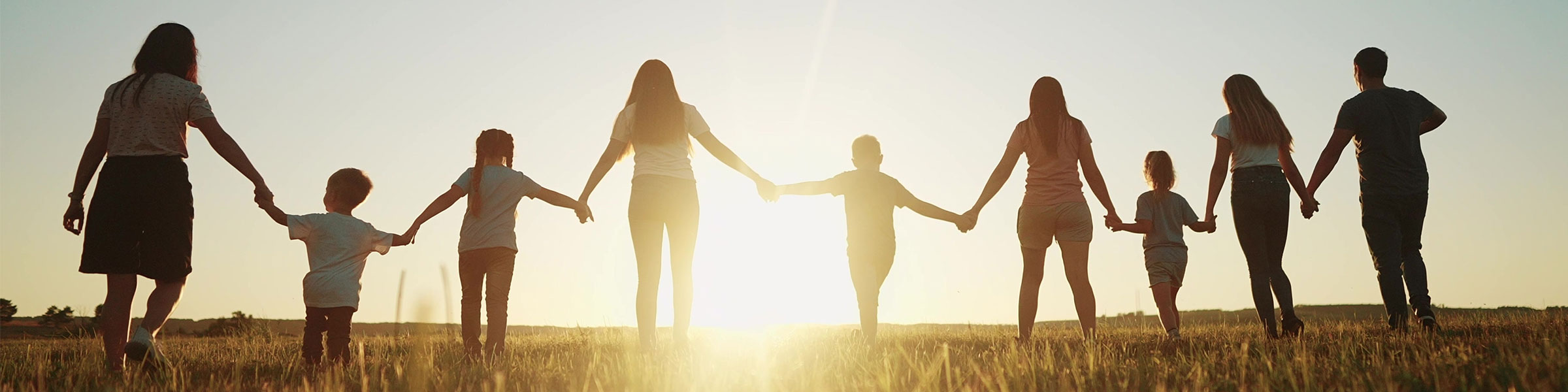 Family group holding hands walking towards sunset