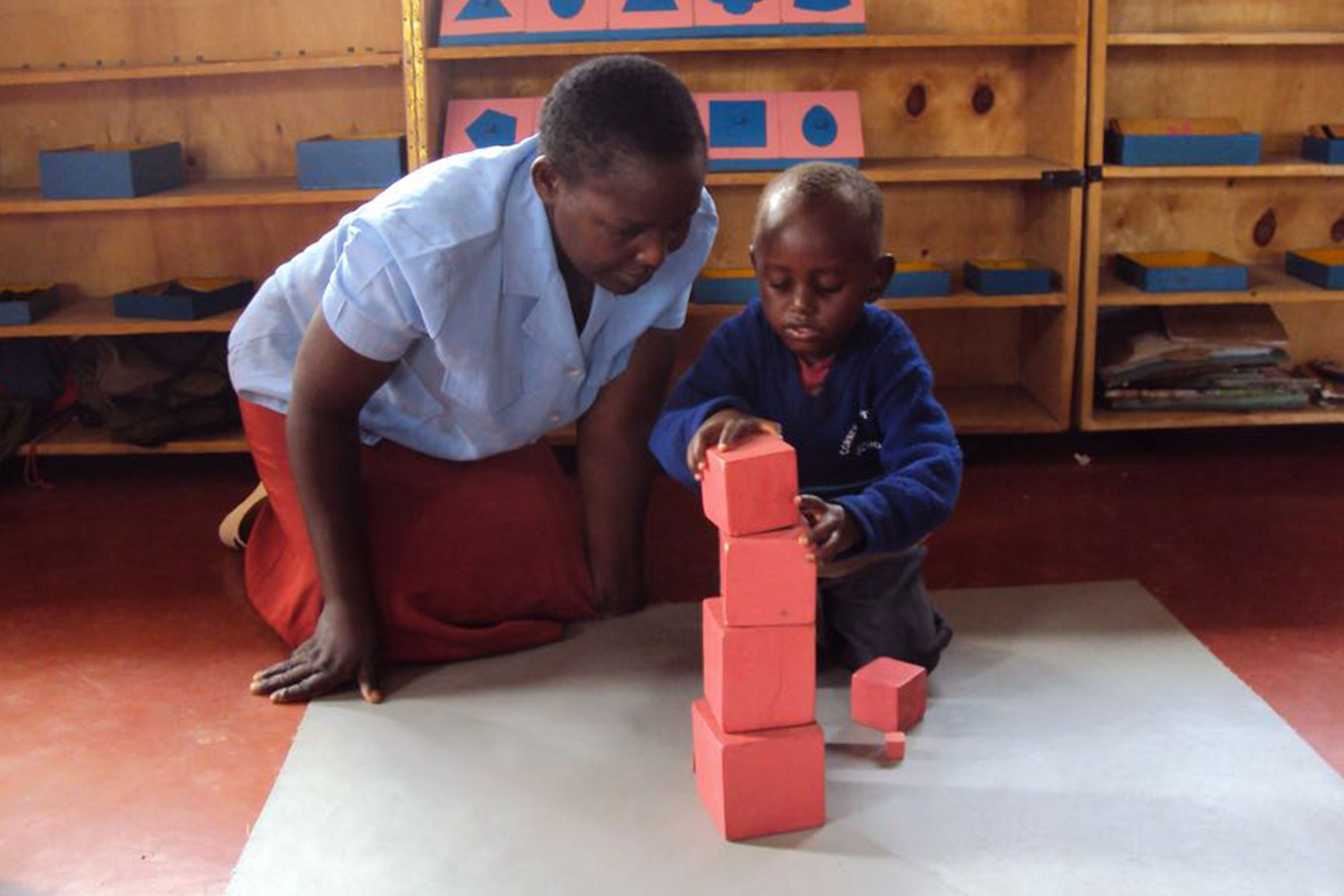Teacher and child with Pink Tower, Corner of Hope Montessori, Kenya