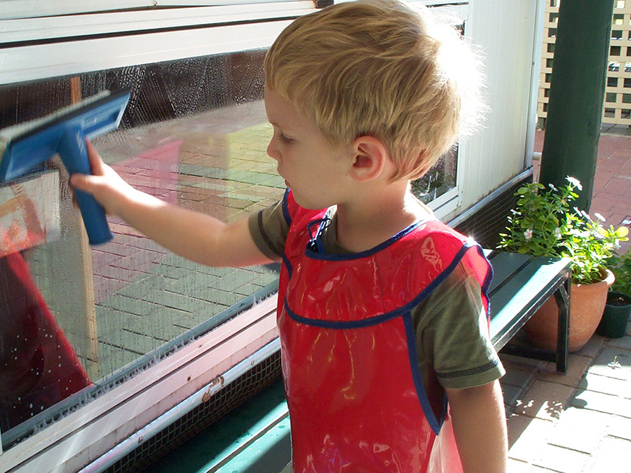 Child washing window in Montessori 3-6 classroom