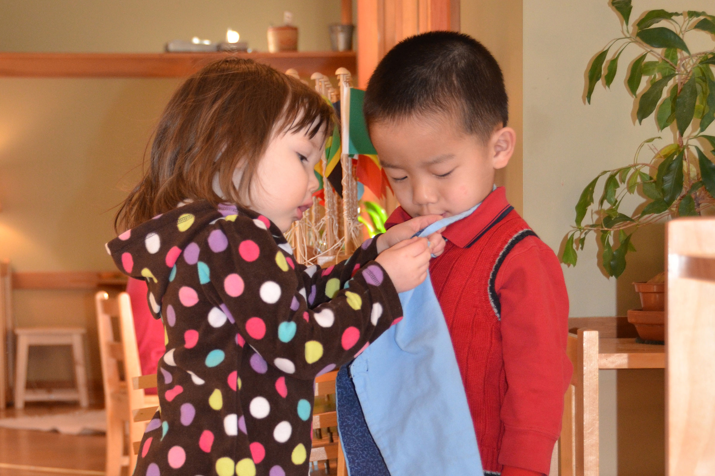 Child helping another putting on apron