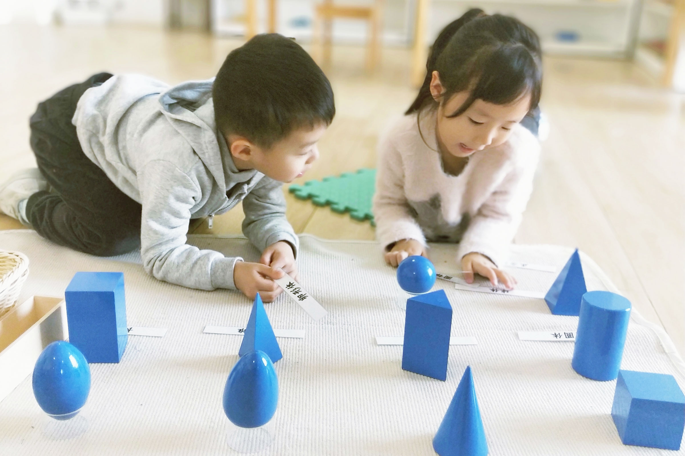 Children working with geometric solids Montessori materials