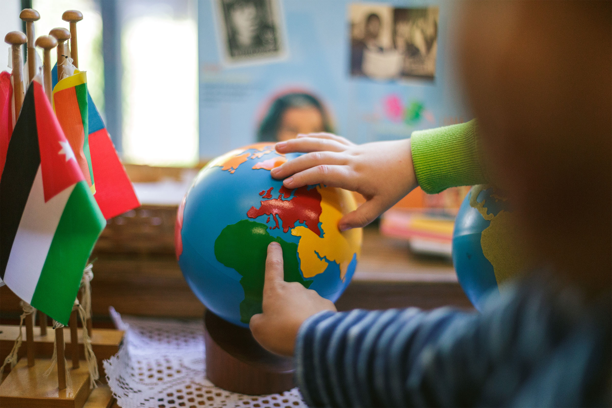 Child's hands on globe in Montessori classroom