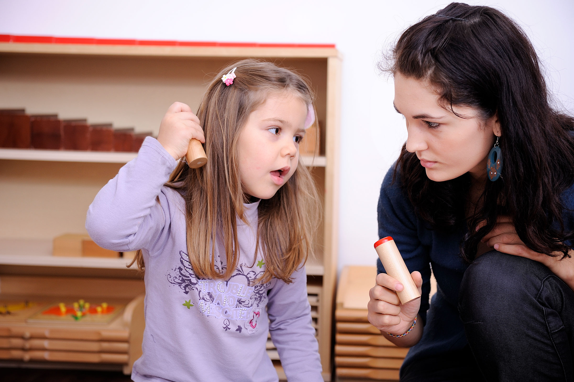 Child and guide working with sensorial Montessori material