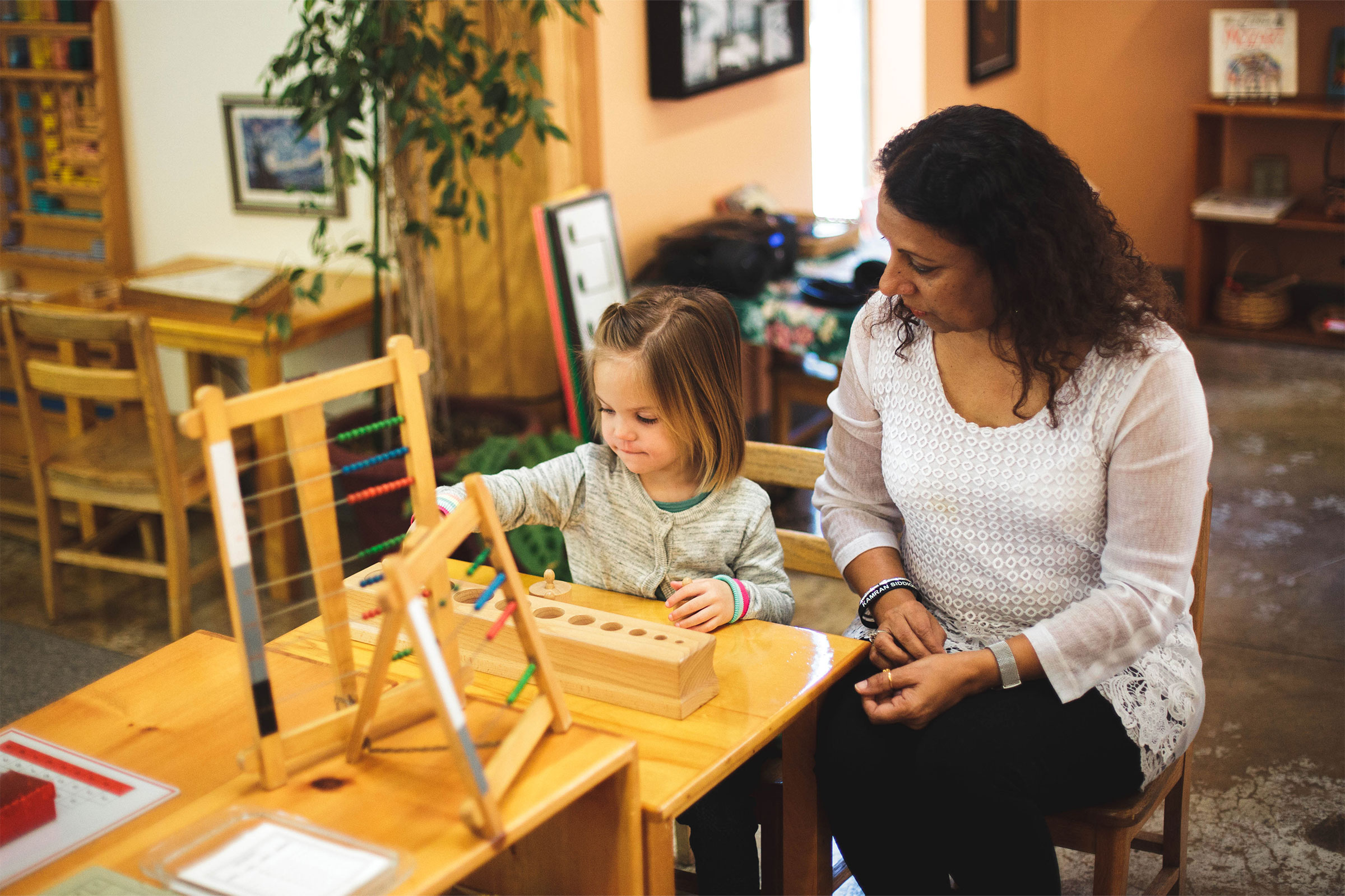 Teacher observing child working on Montessori materials