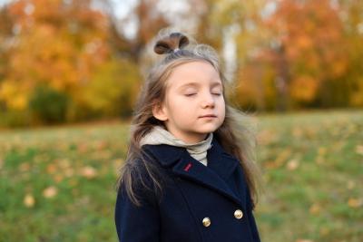 Child outdoors with eyes closed