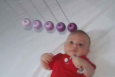 Baby staring up at a mobile of coloured balls