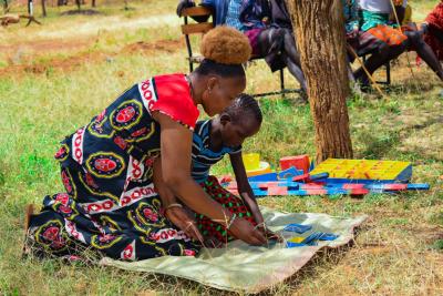 African teacher and child outside working with Montessori materials