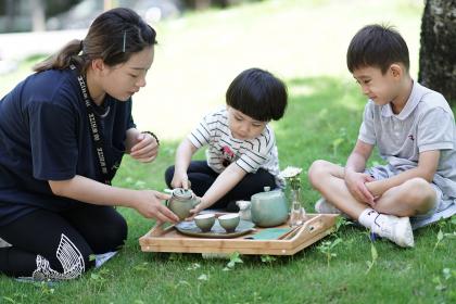 Children with teacher pouring tea outdoors