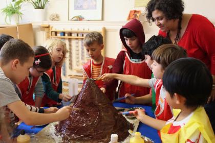 Teacher and children working on volcano model