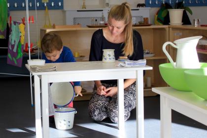 Teacher observing child pouring water